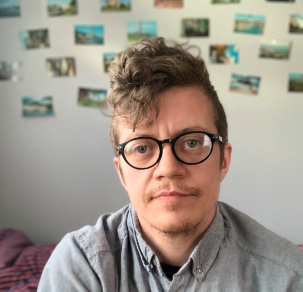 Portrait of the site creator, who has brown wavy hair and glasses.